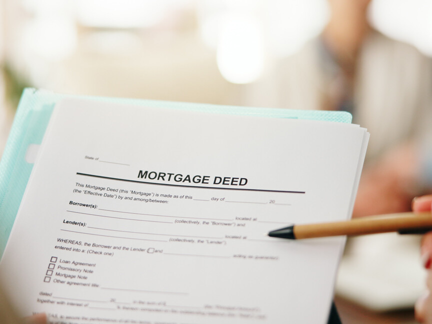 Image of a Mortgage Deed form with someone holding a pen pointing at the paper